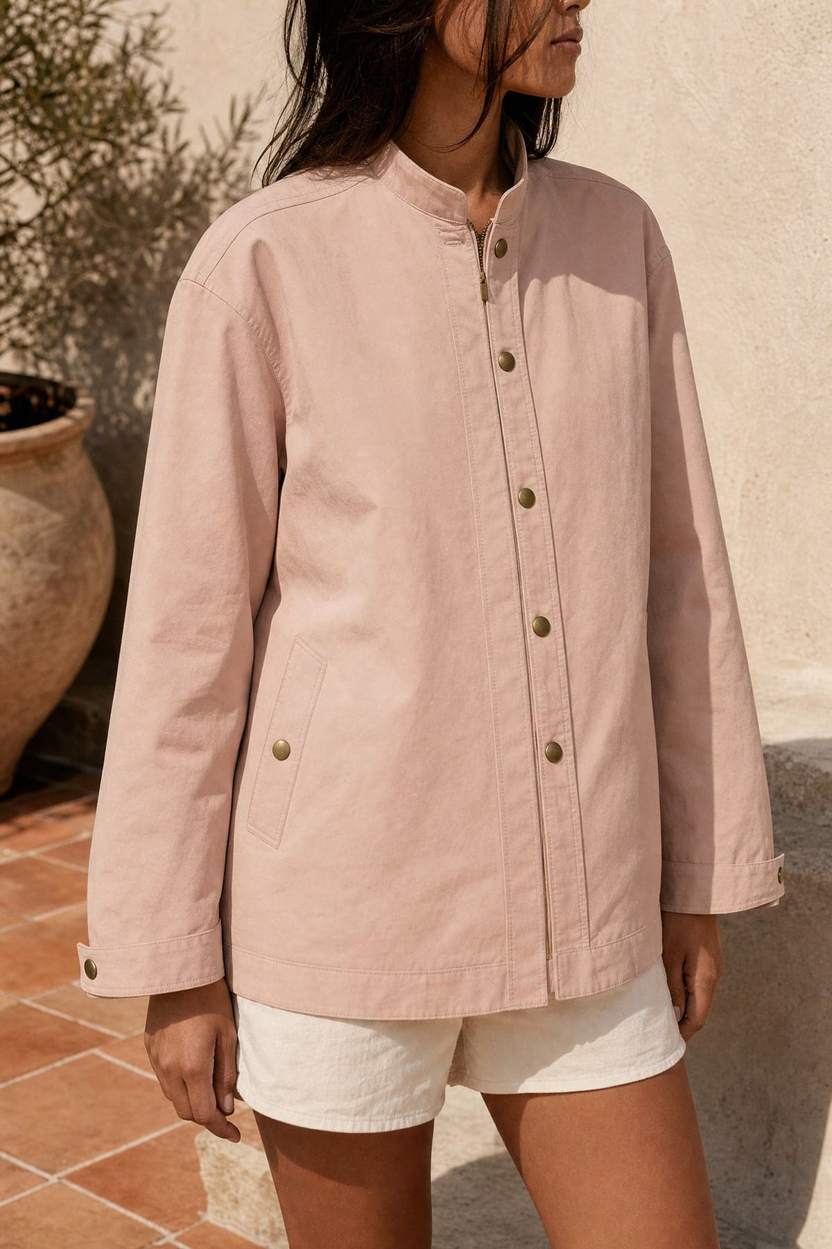 Coach jacket in blush, worn outdoors in warm afternoon light