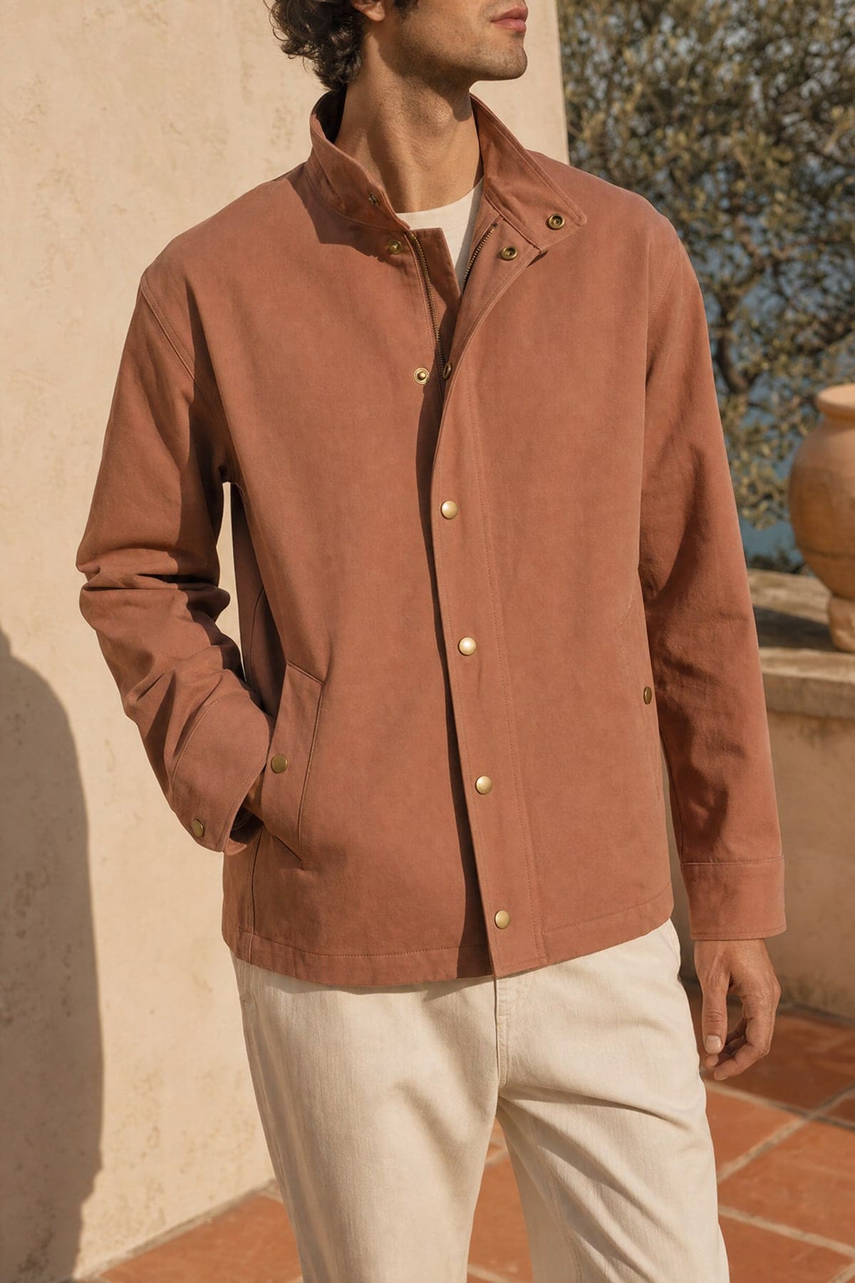 Coach jacket in clay, worn outdoors in warm afternoon light