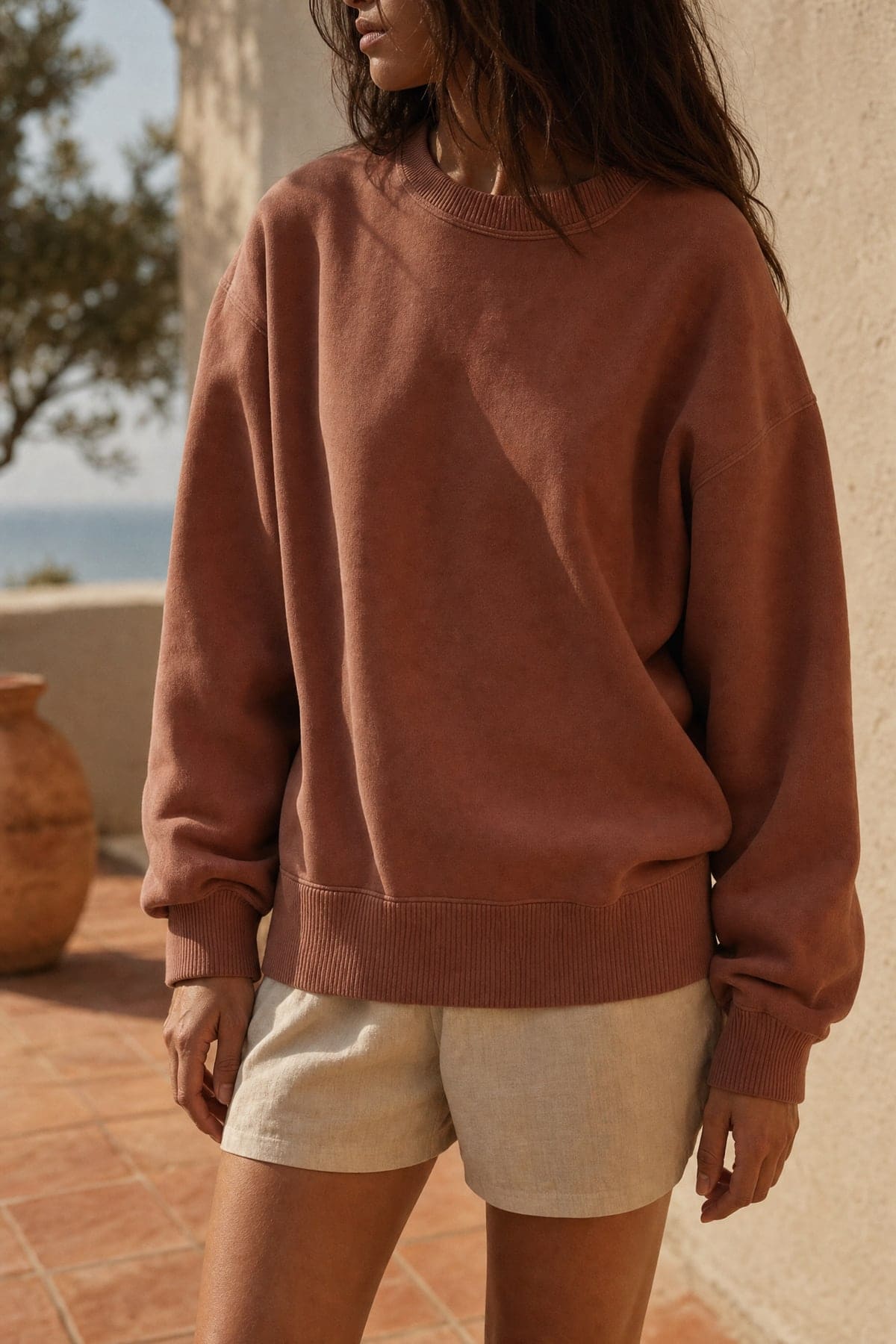 Crewneck in clay, worn outdoors in warm afternoon light