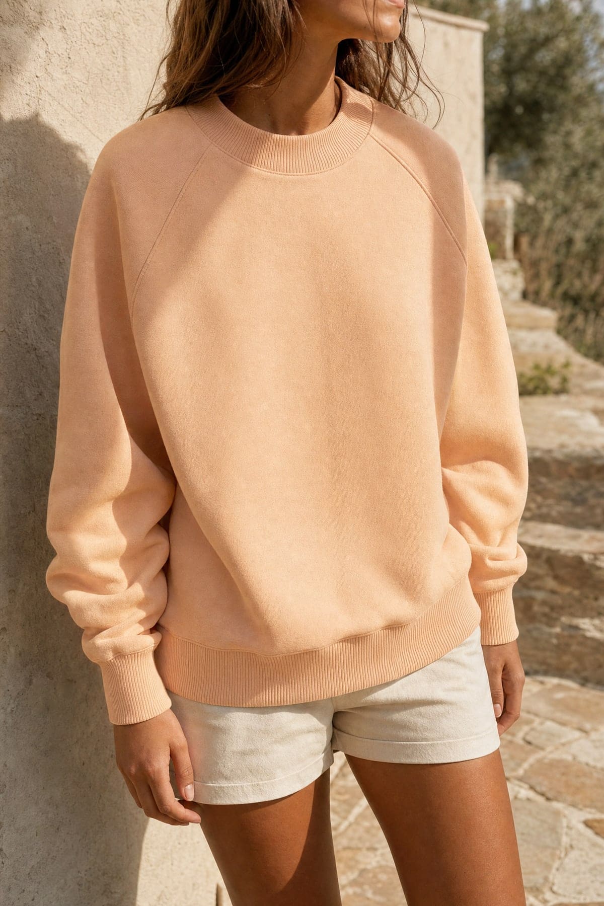 Crewneck in peach, worn outdoors in warm afternoon light