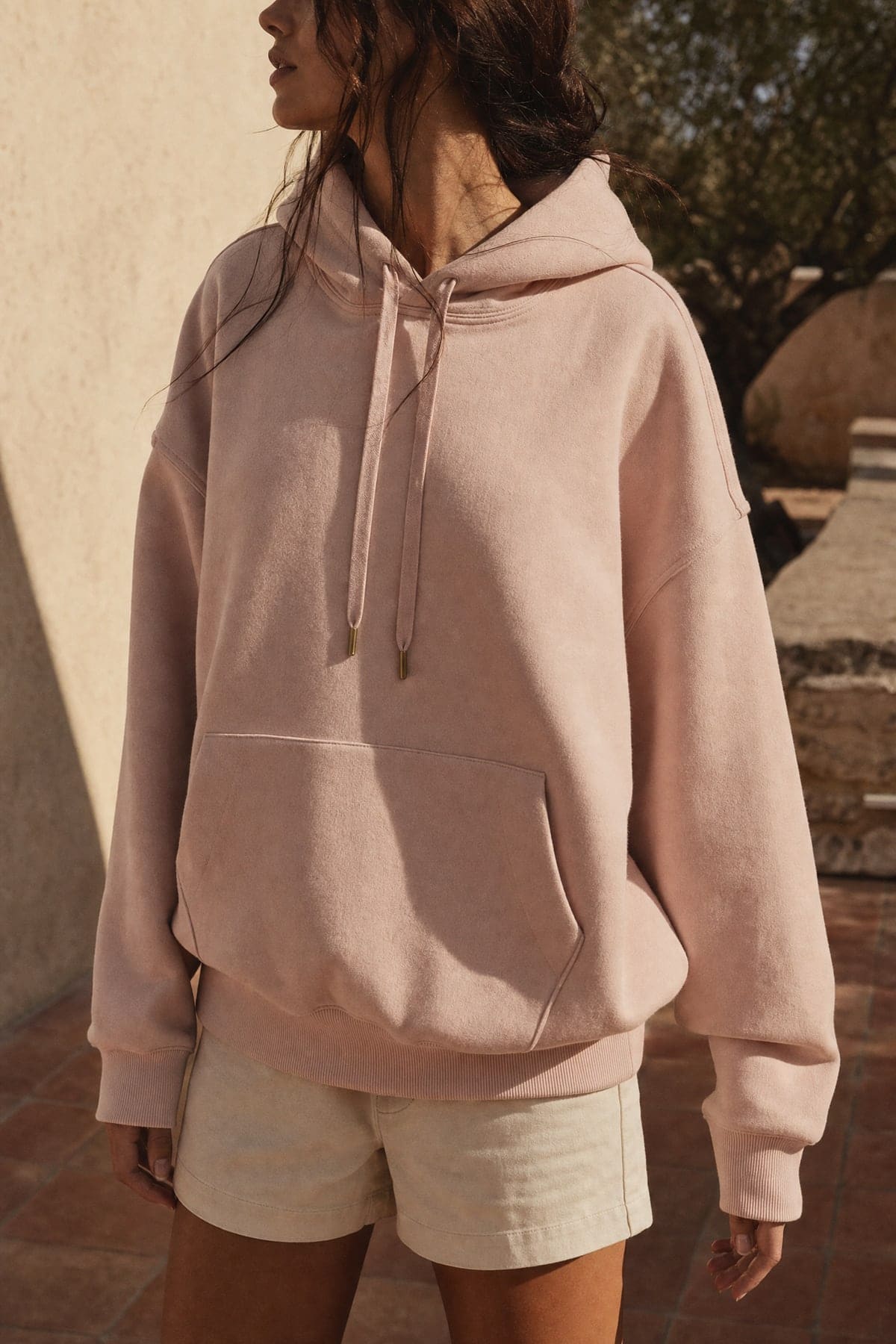 Hoodie in blush, worn outdoors in warm afternoon light