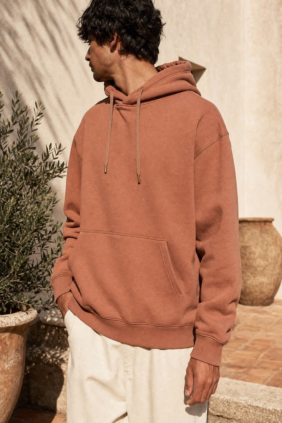 Hoodie in clay, worn outdoors in warm afternoon light