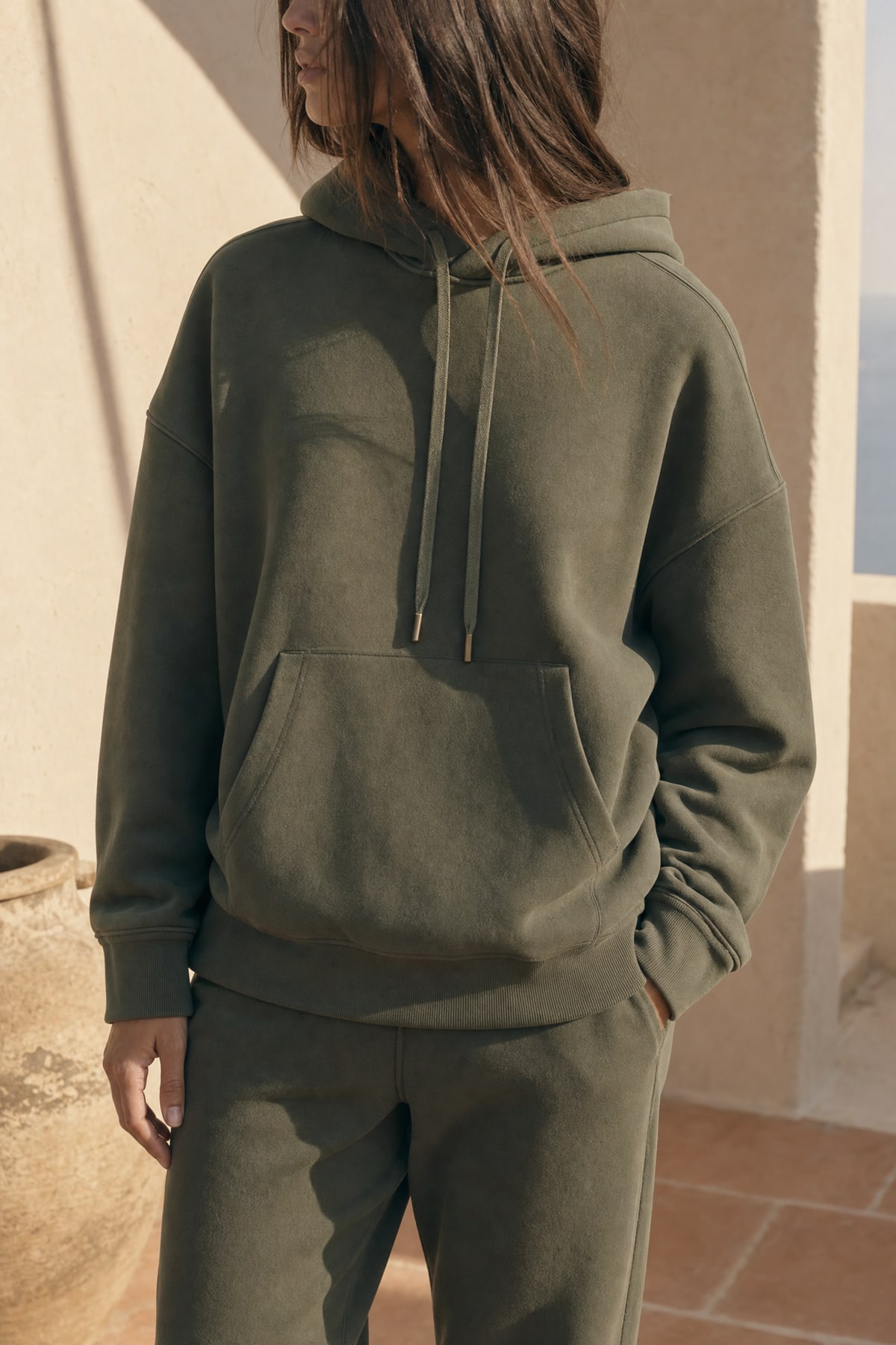 Hoodie in olive, worn outdoors in warm afternoon light
