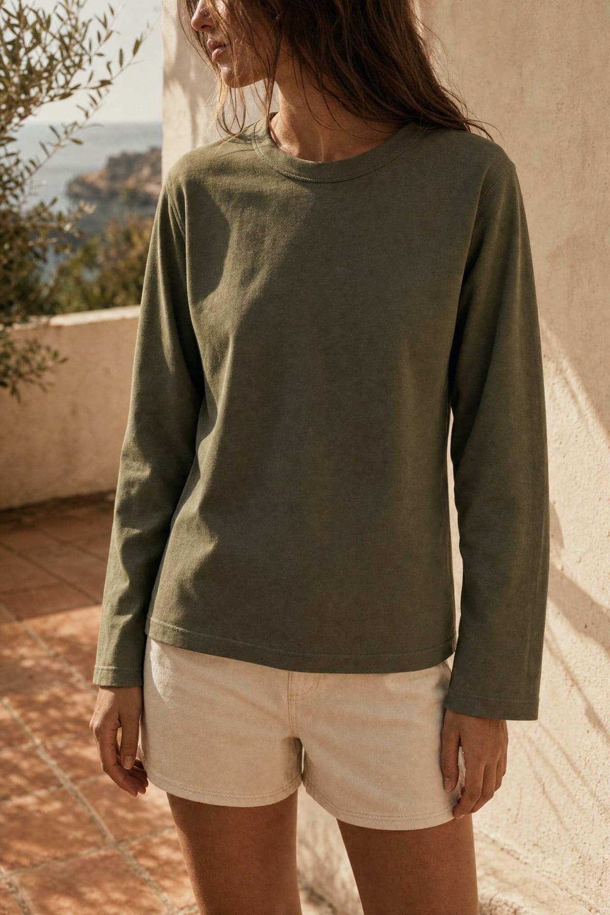 Long-sleeve in olive, worn outdoors in warm afternoon light